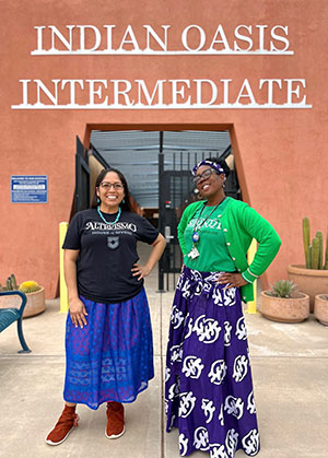 Two staff members in front of school building